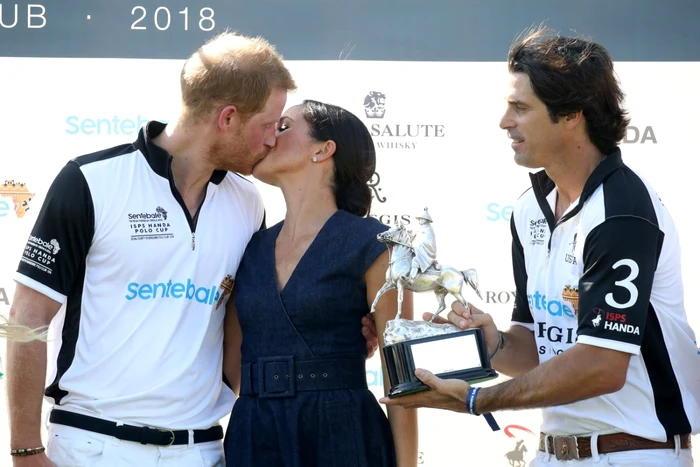 Nacho Figuares de la echipa Sentebale St Regis arată trofeul Sentebale Polo 2018 în timp ce prinţul Harry şi ducesa Meghan se sărută la Royal County of Berkshire Polo Club în Windsor Marea Britanie FOTO Guliver / Getty Images / Chris Jackson