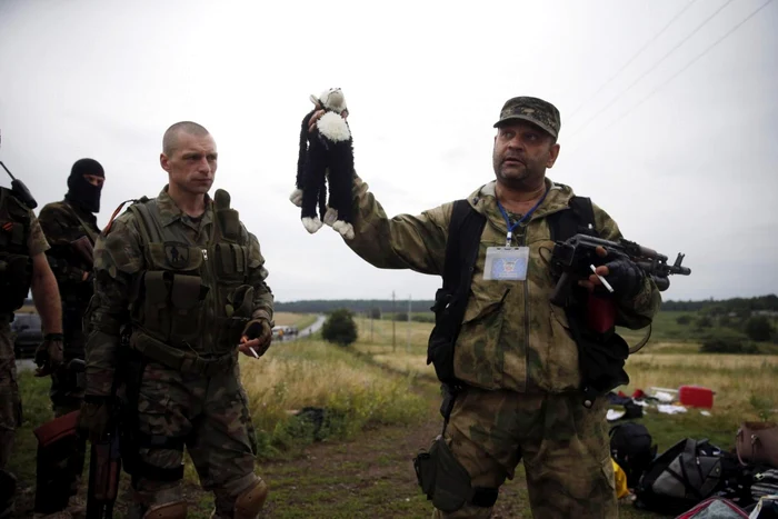 Un separatist prorus ţine în mână o jucărie găsită printre resturile avionului prăbuşit în Ucraina FOTO Wire Photos/Reuters