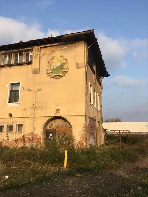 Pe această clădire părăsită, fostă bloc de locuințe pentru muncitorii din port, se află stema comunistă