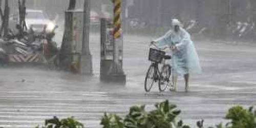 Un bărbat cu bicicleta înfruntă furia  taifunului Soudelor pe o stradă din Taipei Taiwan FOTO AP