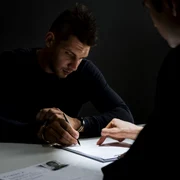 Consilier probațiune - deținut = barbat cu catuse semneaza un document