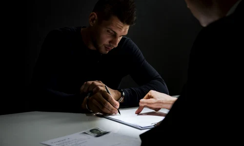 Consilier probațiune - deținut = barbat cu catuse semneaza un document