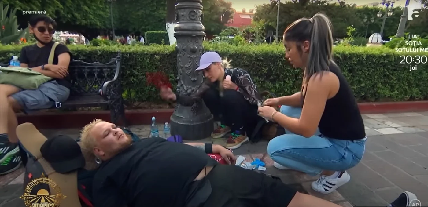 Pufeh de la America Express, întins pe stradă, primește ajutor de la medic