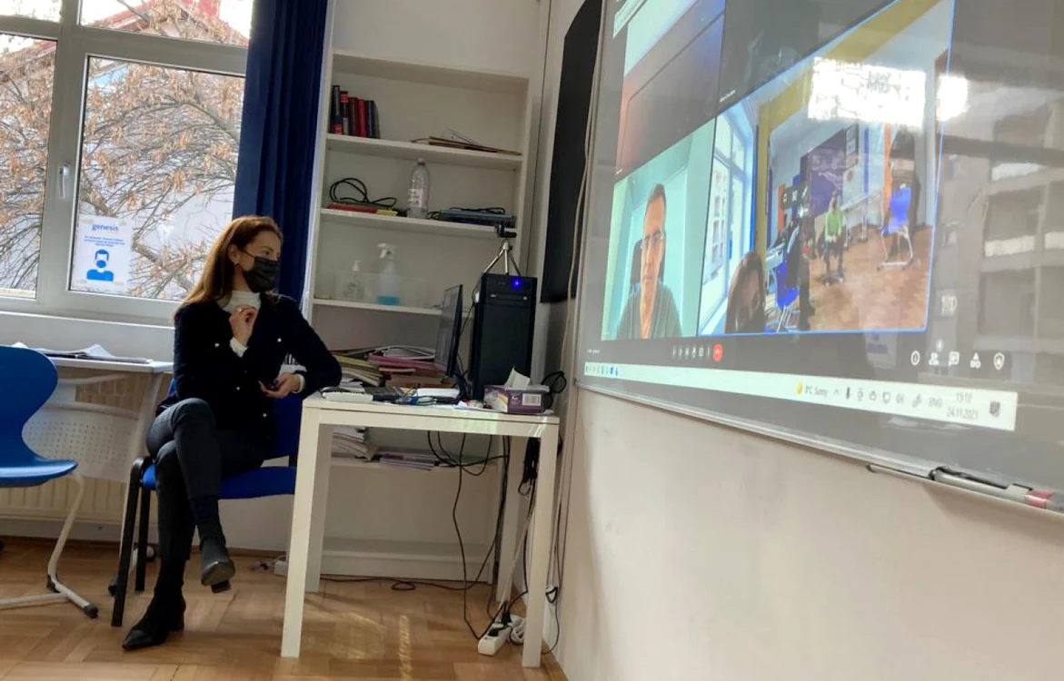 A person sitting at a desk in front of a large screenDescription automatically generated with medium confidence