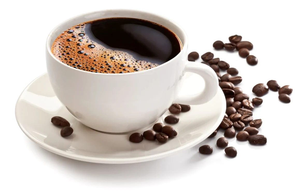 O cană albă cu cafea și boabe de cafea lângă