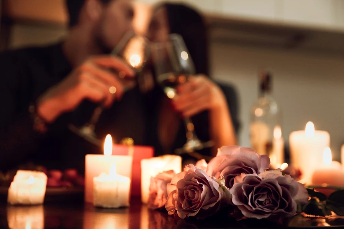 Doi tineri ciocnesc un pahar la o cină romantică