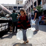 O fată palestiniană cară bidoane cu apă în Jabalia, Fâșia Gaza
