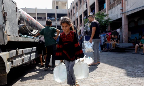 O fată palestiniană cară bidoane cu apă în Jabalia, Fâșia Gaza
