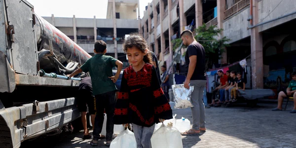O fată palestiniană cară bidoane cu apă în Jabalia, Fâșia Gaza