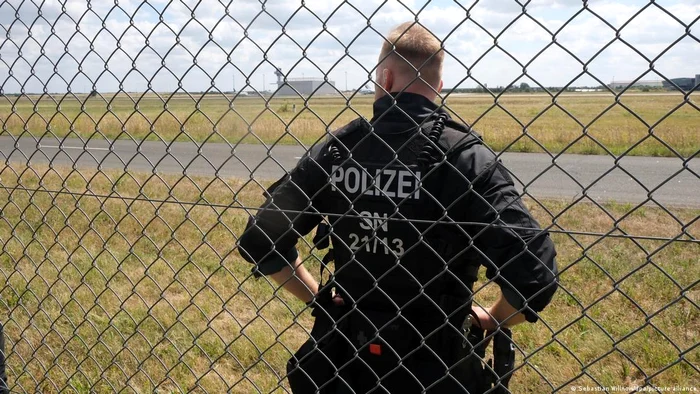 Un polițist în incinta aeroportului Leipzig în timpul misiunii de identificare a resturilor dronei