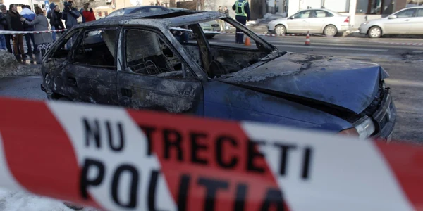 O masina incendiata este analizata de politistii criminalist