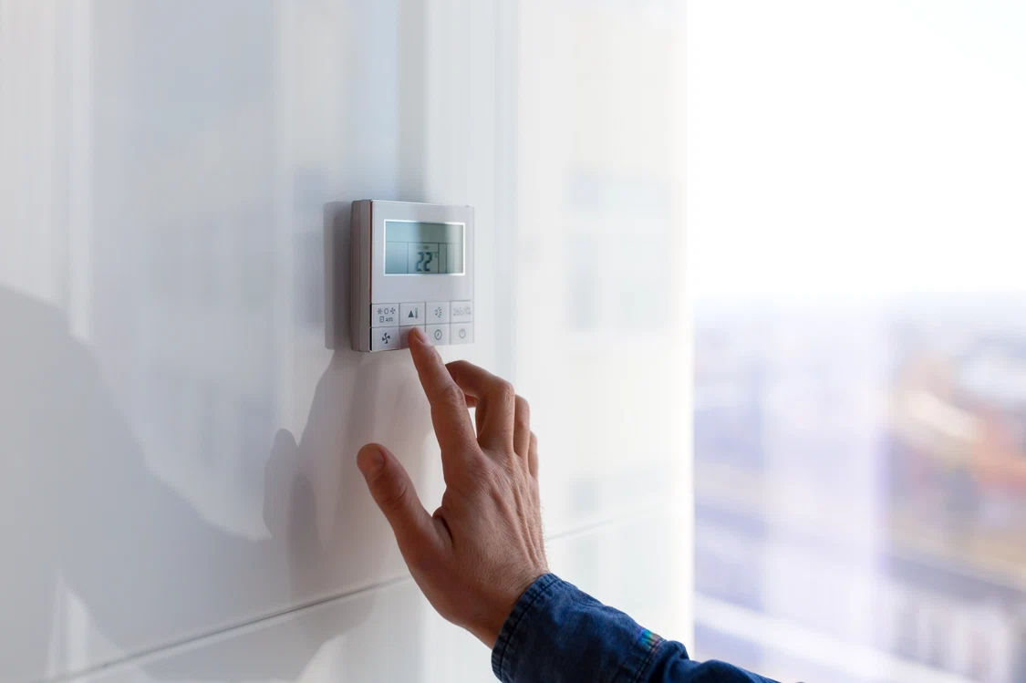 Un bărbat micșorează temperatura din încăpere pentru a reduce consumul de energie
