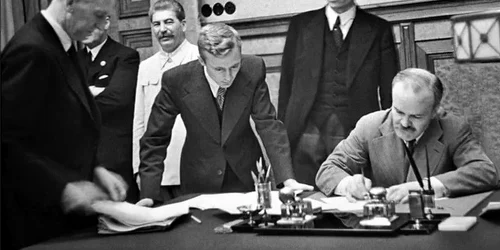 Veaceslav Molotov semnează Pactul de neagresiune cu Germania nazistă, în prezența lui Iosif Stalin (foto: Wikimedia Commons)