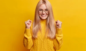 happy joyful blonde woman clenches fists celebrates good result smiles broadly being high spirit makes triumph gesture wears spectacles winter sweater jpg