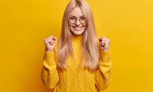 happy joyful blonde woman clenches fists celebrates good result smiles broadly being high spirit makes triumph gesture wears spectacles winter sweater jpg