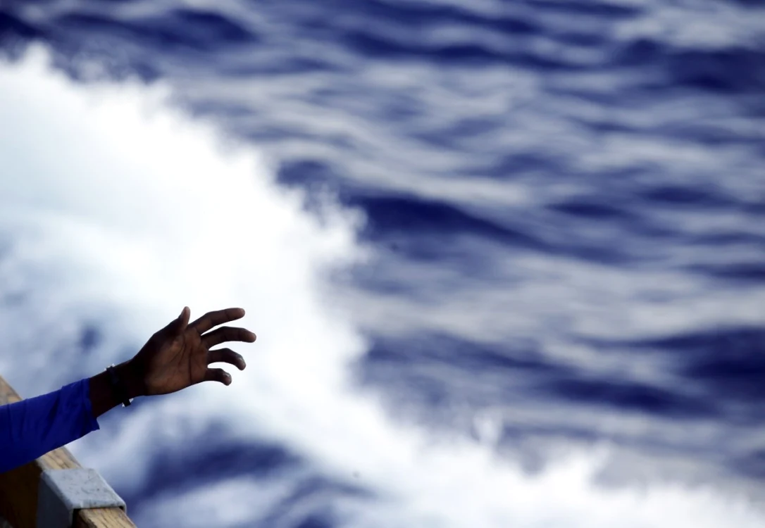 Un emigrant intinde braţul de pe puntea de navei belgiene Godetia după ce a fost salvat în timpul unei misiuni de căutare şi salvare în Marea Mediterană FOTO AP / Arhivă