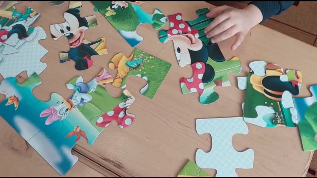 Mâinile unui copil care așează bucățele dintr-un puzzle la grădiniță