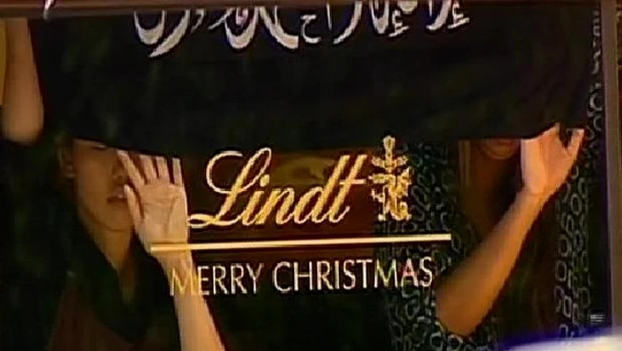 
    Ostaticii ţin mâinile ridicate pe geamul unei vitrineCaptură video  