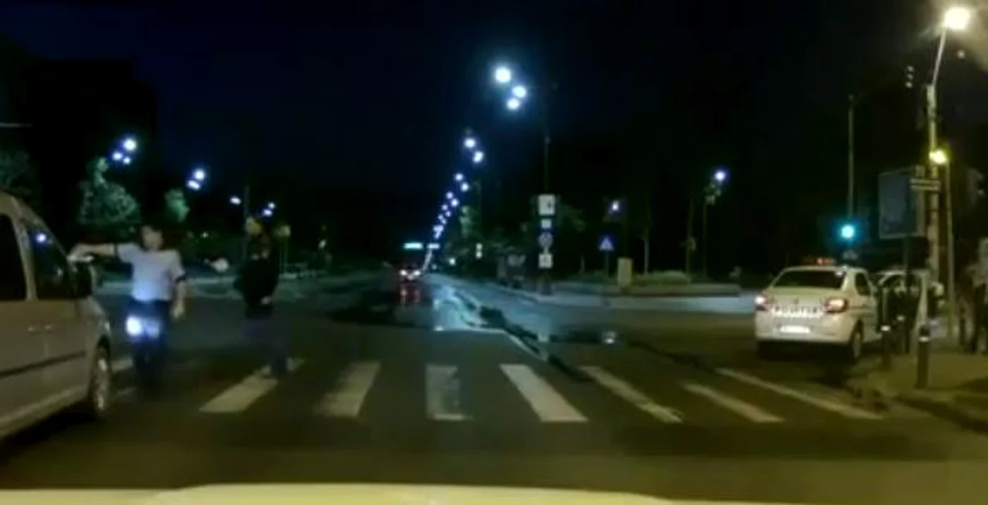 În această imagine se poate vedea cum un polițist toarnă o sticlă cu apă pe o persoană care caută refugiu în fața unei dubițe (Digi24)