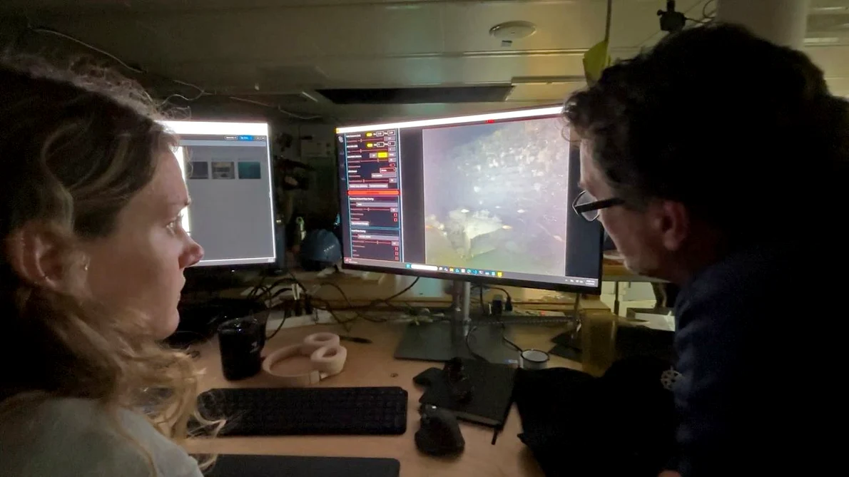 Specialiștii în imagistică WHOI, Dwight Coleman (dreapta) și Zoe Daheron, urmăresc cum imaginile în timp real ale epavei navei Quest sunt transmise de pe fundul mării (© Ken Kostel / Woods Hole Oceanographic Institution)