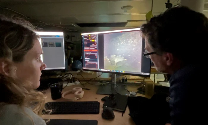 Specialiștii în imagistică WHOI, Dwight Coleman (dreapta) și Zoe Daheron, urmăresc cum imaginile în timp real ale epavei navei Quest sunt transmise de pe fundul mării (© Ken Kostel / Woods Hole Oceanographic Institution)