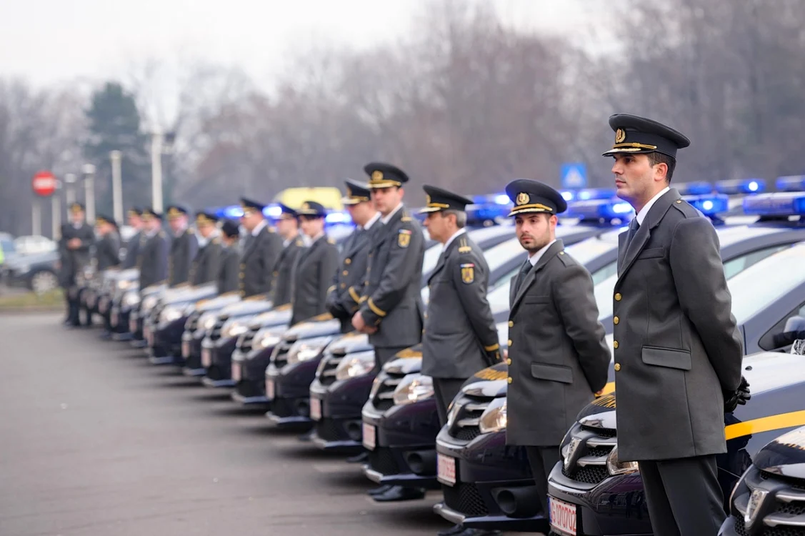 Angajați ANAF aliniați în uniforme în fața mașinilor pe care scrie Antifraudă