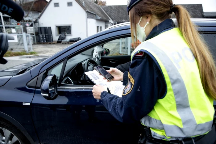 FOTO: afp / Un ofiţer de poliţie verifică certificatul digital de vaccinare al unui şofer în timpul unui control în trafic în Graz, Austria, 15 noiembrie 2021