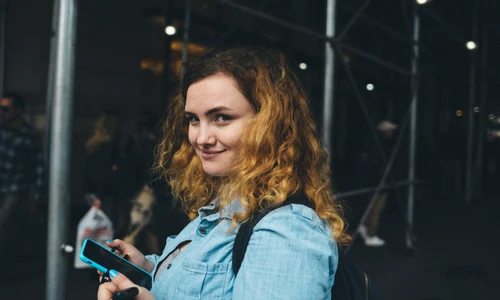 femeie zambitoare cu smartphone in mana jpg