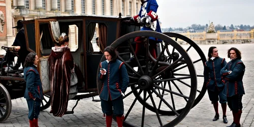 Câteva persoane aşteaptă lângă trăsura în timpul filmărilor show-ului Versaille FOTO AP