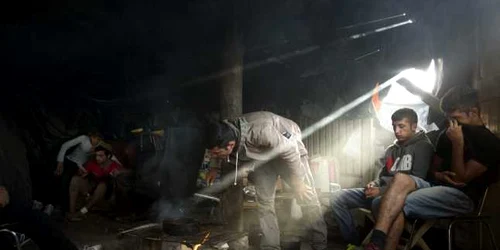 Emigranţi afgani coc mâncare într-un cort pe un camp lângă Calais nordul Franţei FOTO AP