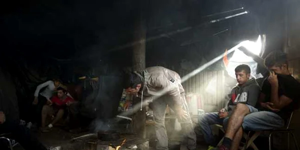 Emigranţi afgani coc mâncare într-un cort pe un camp lângă Calais nordul Franţei FOTO AP