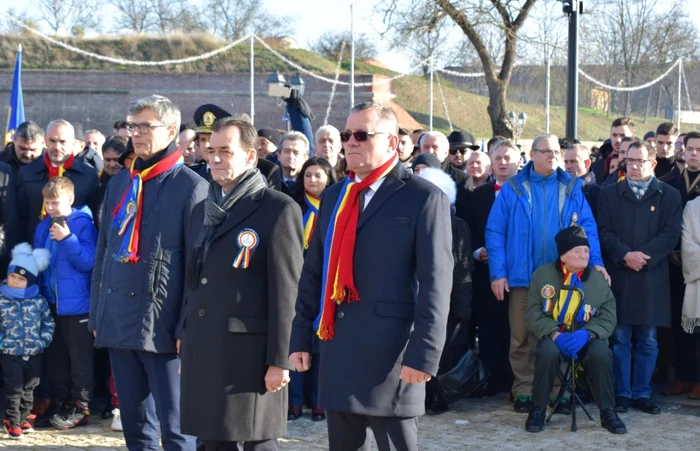 Veteranul Laurean Deac stă pe un scaun în timp ce premierul Ludovic Orban depune o coroană de flori