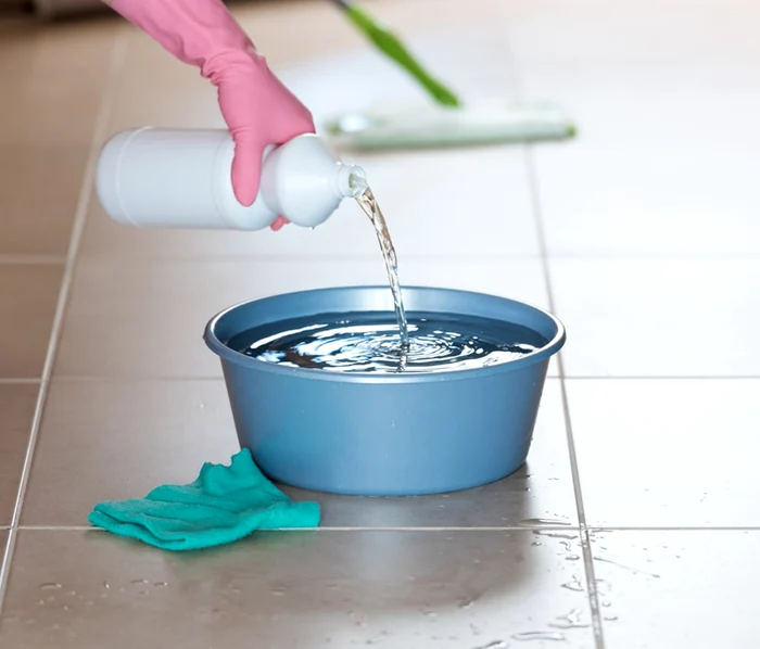 Un lighean cu apă pe o podea din gresie în care se pune un înălbitor pentru curățenie Swipe N Clean