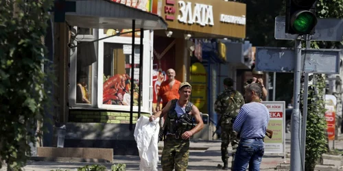 Separatişti pro-ruşi înarmaţi sta lângă corpul unui bărbat ucis recent de un obuz în Doneţc Ucraina FOTO Reuters