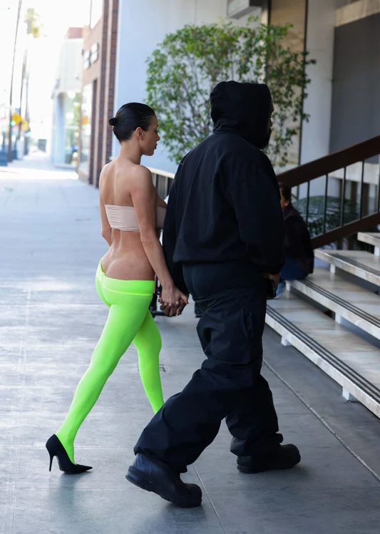 Bianca Censori ținându-se de mână cu Kanye West. Ea este îmbrăcată în colanți verzi și bustieră bej