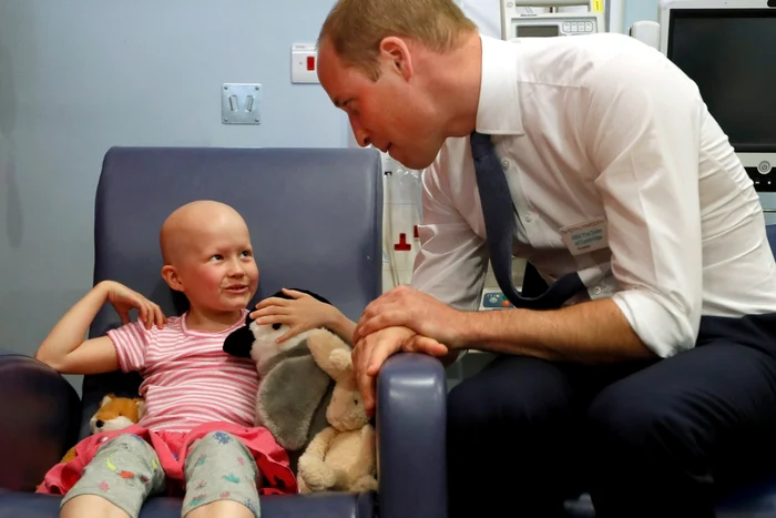 Prinţul William Duce de Cambridge discută cu pacienta Daisy Wood în vârstă de 6 ani în timpul unei vizite la spitalul Royal Marsden în Sutton Anglia FOTO Guliver / Getty Images / Kirsty Wigglesworth