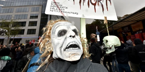 Un protestatar cu o mască pe faţă demonstrează împotriva Acordului de liber schimb TTIP (Transatlantic Comerţ şi Parteneriatul de Investiţii) în timpul summitului UE de la Bruxelles