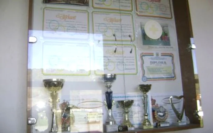 Pe holul Şcolii Voloiac, la loc de ciste stau diplomele şi trofeele obţinute de elevii  antrenaţi de profesorul Valentin Drăghici