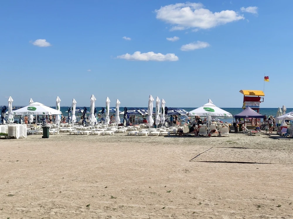 Plajă pe litoralul românesc amenajată cu umbreluțe albe