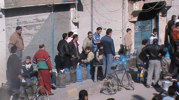 Sirieni care aşteaptă umplerea buteliilor în Deir Balaba, în apropiere de Homs. 