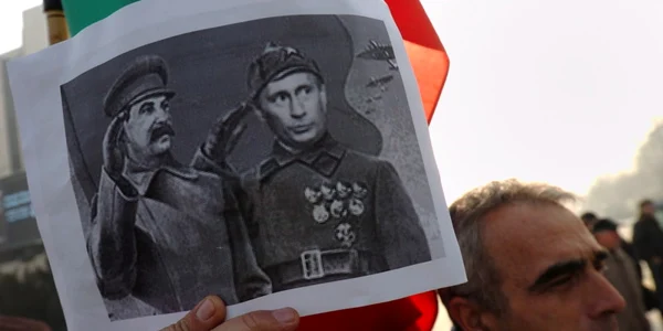 Un barbat tinand in mana o pancarda cu Putin si Stalin FOTO EPA-EFE