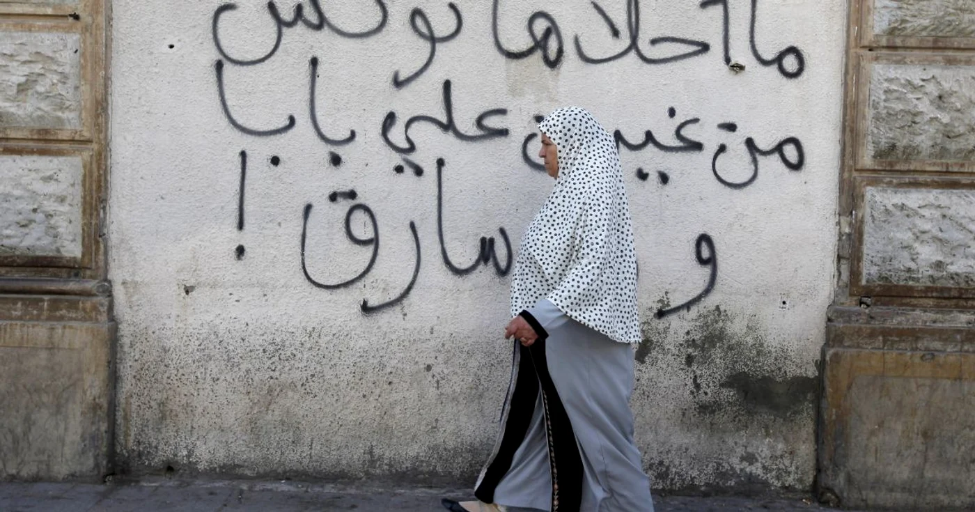 O femeie trece prin dreptul unui graffiti în Tunis. Tunisia este țara arabă cea mai progresistă în privinţa drepturilor femeilor.