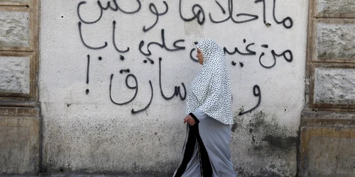 O femeie trece prin dreptul unui graffiti în Tunis. Tunisia este țara arabă cea mai progresistă în privinţa drepturilor femeilor.