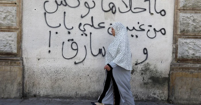 O femeie trece prin dreptul unui graffiti în Tunis. Tunisia este țara arabă cea mai progresistă în privinţa drepturilor femeilor.