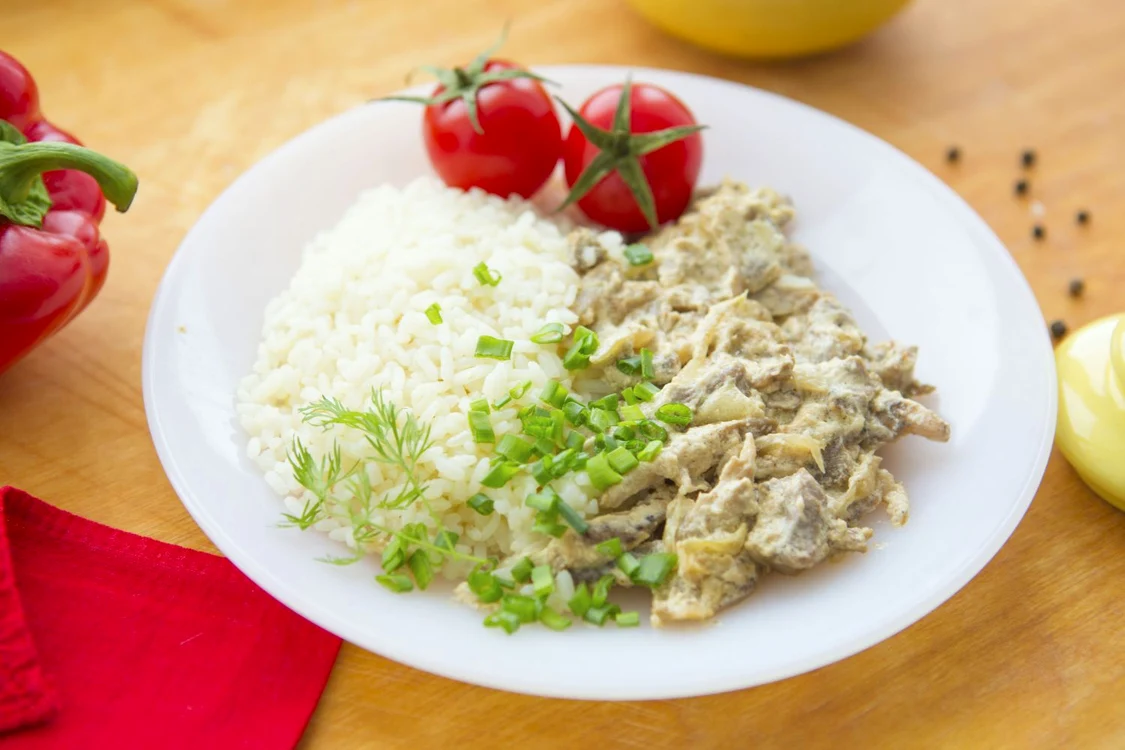 73210440   stewed beef and rice on the white plate on wooden background  jpeg