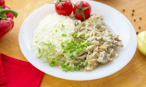 73210440   stewed beef and rice on the white plate on wooden background  jpeg