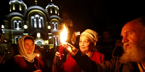 Credincioşi creştini ortodocşi ucrainieni iau lumină din Focul Sfânt adus de la Ierusalim la Catedrala Sf Volodymyr în timpul ceremoniei religioase de Paşte la Kiev Ucraina FOTO AP