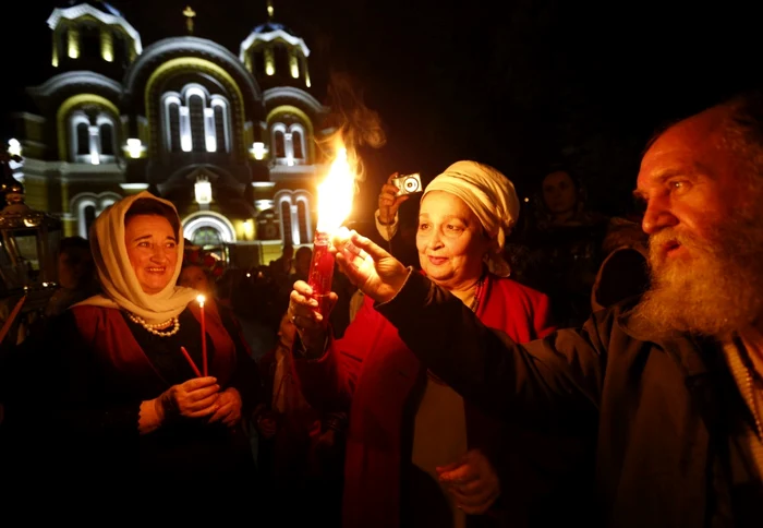 Credincioşi creştini ortodocşi ucrainieni iau lumină din Focul Sfânt adus de la Ierusalim la Catedrala Sf Volodymyr în timpul ceremoniei religioase de Paşte la Kiev Ucraina FOTO AP