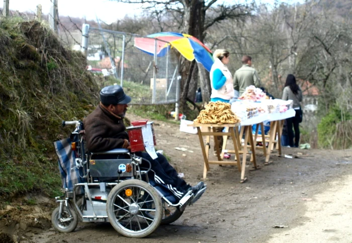 Adus într-un scaun cu rotile, un cerşetor apelează la mila pelerinilor veniţi la Prislop. FOTO: D.G.