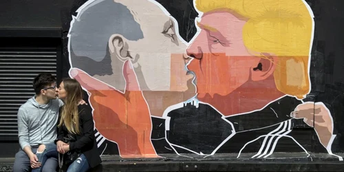 Un cuplu de îndrăgostiţi se sărută în faţa unui perete pe care sunt pictaţi preşedintele Rusiei Vladimir Putin care îl sărută pe candidatul republican la preşedenţia Statelor Unite Donald Trump. FOTO AP